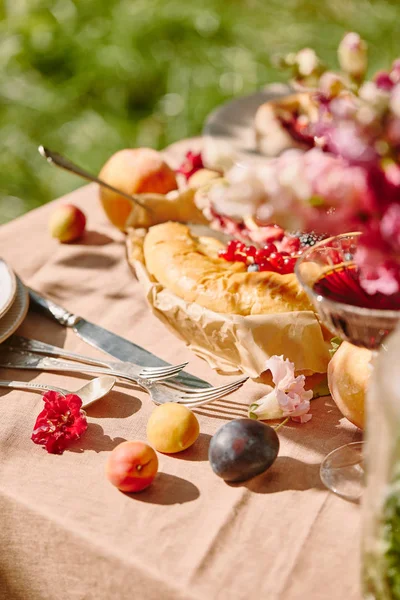 Сливы, посуда и пирог на столе в саду — стоковое фото