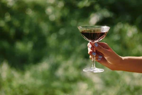 Cropped image of woman holding wineglass above green grass — Stock Photo