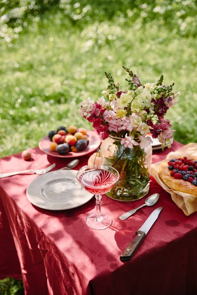 Verre à vin et bouquet de fleurs sur la table dans le jardin — Photo de stock