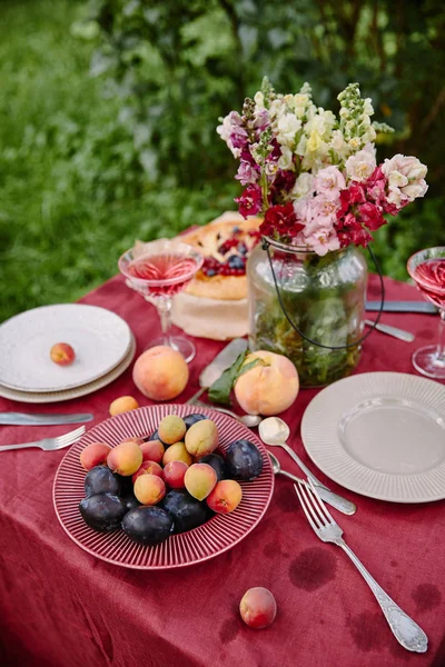 Frutas maduras y ramo de flores en la mesa en el jardín - foto de stock