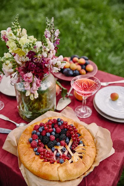 Tarta de bayas y ramo de flores en la mesa en el jardín - foto de stock