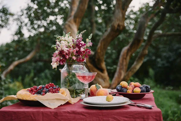 Bouquet of flowers, fruits and tasty pie on table in garden — Stock Photo