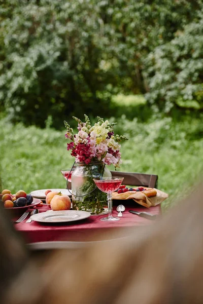 Bouquet of flowers and fruits on table in garden — Stock Photo