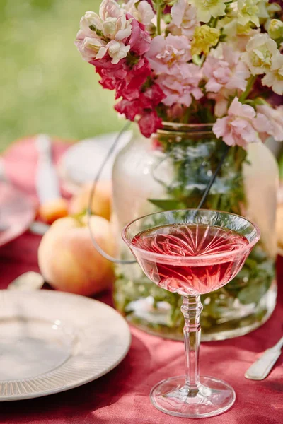 Vino y ramo de flores en la mesa en el jardín - foto de stock