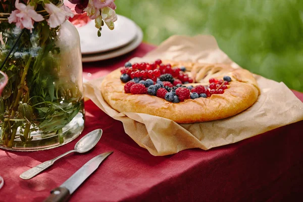 Torta appetitosa con lamponi, ribes e mirtilli sul tavolo in giardino — Foto stock