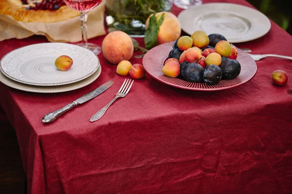 Фрукты, тарелки и посуда на столе в саду — стоковое фото