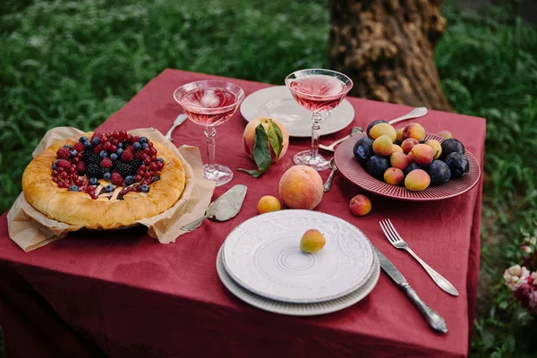 Келихи вина, апетитний ягідний пиріг і фрукти на столі в саду — стокове фото