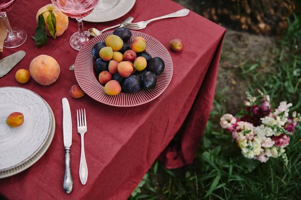 Vue grand angle de la plaque avec prunes et abricots sur la table dans le jardin — Photo de stock