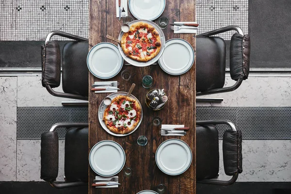 Vista superior de varias pizzas en bandejas y mesa en el restaurante - foto de stock