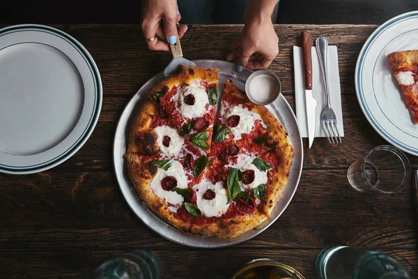 Recortado tiro de servir pizza recién horneada en el restaurante - foto de stock