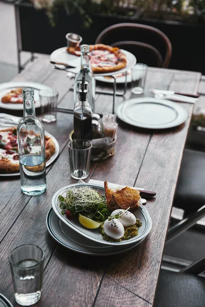 Deliciosa ensalada y pizza en la mesa en el restaurante moderno - foto de stock