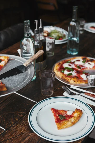 Tasty pizza and water on table at modern restaurant — Stock Photo