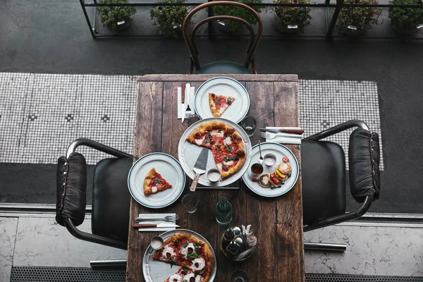 Top view of delicious pizza and curd pancakes on wooden table at restaurant — Stock Photo