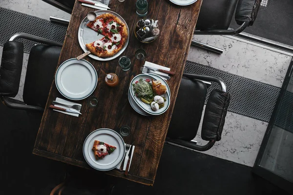 Vista superior de deliciosa pizza e salada em mesa de madeira no restaurante — Fotografia de Stock