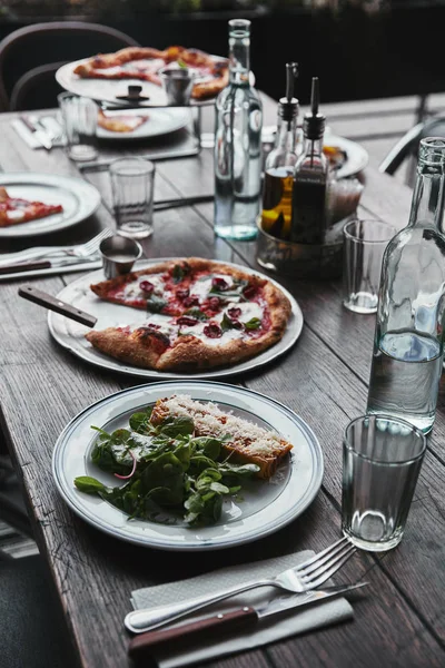 Sabrosos platos italianos y bebidas en la mesa rústica de madera en el restaurante - foto de stock