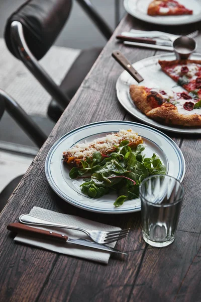 Close-up shot of delicious pizza and lasagne on wooden table — Stock Photo