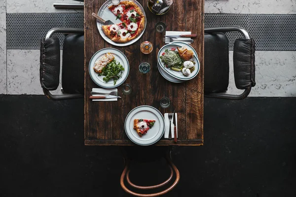 Вид на вкусные итальянские блюда и напитки на деревянном деревенском столе в ресторане — стоковое фото