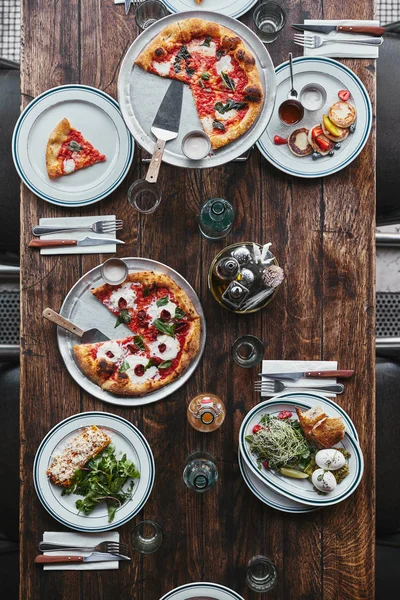 Vista superior de vários pratos italianos saborosos e bebidas em mesa rústica de madeira no restaurante — Fotografia de Stock