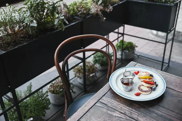 Curd pancakes with bowls of dippings and cutlery on wooden table at restaurant — Stock Photo