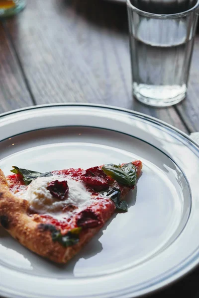 Close-up shot of tasty pizza margherita on white plate with glass of water — Stock Photo