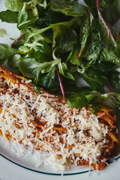 Delicious lasagne with green leaves on rustic wooden teable — Stock Photo