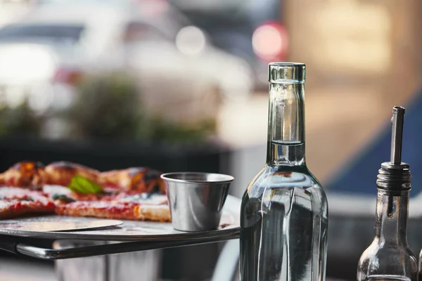 Primer plano de deliciosa pizza en bandeja y botella de agua en el restaurante - foto de stock