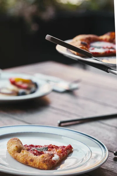 Delicious sliced pizza margherita on metal tray and plate at restaurant — Stock Photo