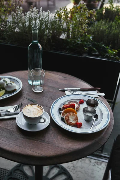 Syrniki con café y ensalada en la mesa de madera en el restaurante - foto de stock