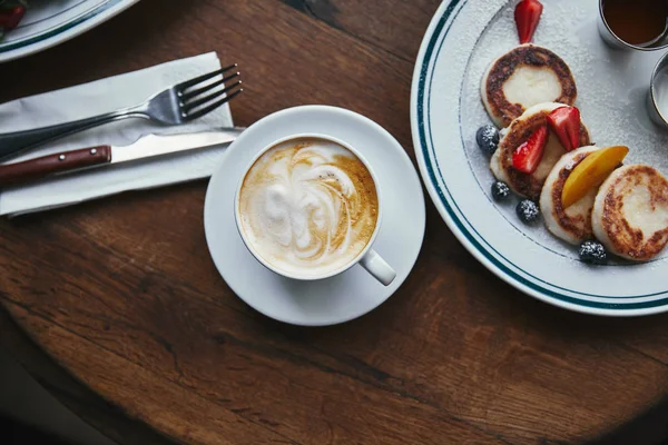 Vue du dessus de tasse de café et de sironiki avec des baies sur la table en bois — Photo de stock