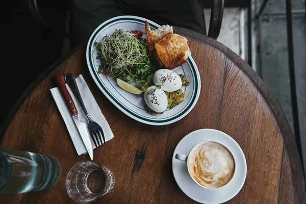 Vista superior de la ensalada saludable con brotes y huevos en la mesa de madera en el restaurante con taza de café - foto de stock