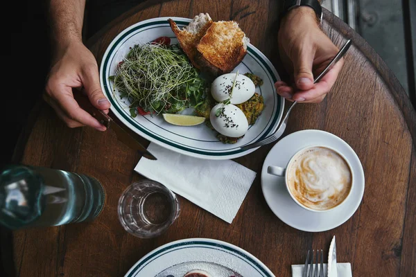 Обрезанный снимок человека, поедающего здоровый салат с капустой и кофе в ресторане — стоковое фото