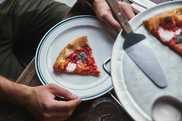 Cropped shot of man eating delicious pizza margherita at restaurant — Stock Photo