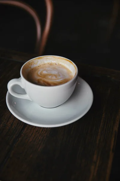 Close-up shot of cup of delicious coffee on rustic wooden table at restaurant — Stock Photo