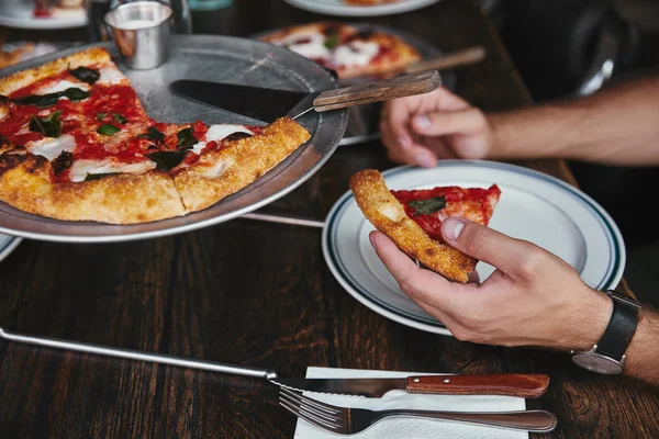 Обрізаний знімок людини, що їсть смачну піцу в ресторані — стокове фото