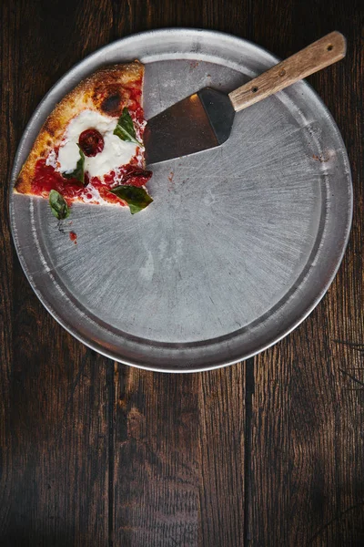 Vista superior de fatia de pizza com servidor em bandeja de metal e mesa de madeira — Fotografia de Stock