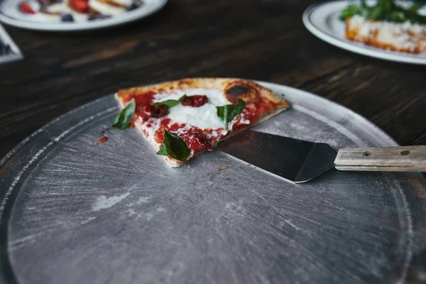 Slice of tasty pizza with server on metal tray and wooden table — Stock Photo