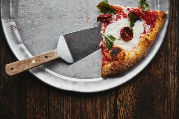 Top view of slice of tasty pizza with server on metal tray and wooden table — Stock Photo