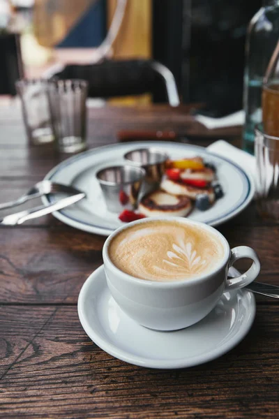Primer plano de delicioso syrniki en el plato y la taza de café en la mesa de madera rústica - foto de stock