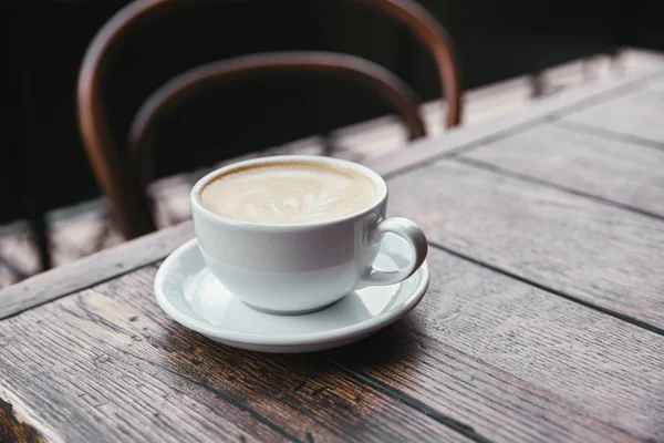 Close-up shot of cup of fresh coffee on rustic wooden table at restaurant — Stock Photo