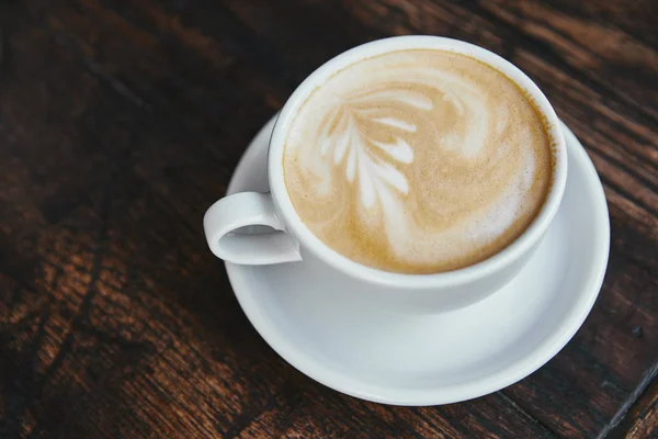 Taza de café fresco con arte latte en la mesa de madera rústica - foto de stock