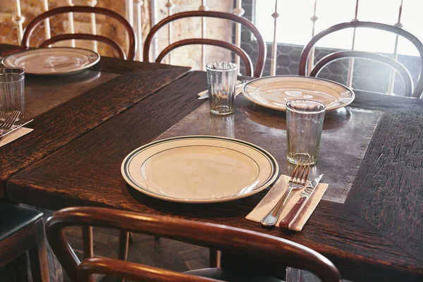 Primer plano de los platos con cubiertos y vasos en la mesa en el restaurante - foto de stock
