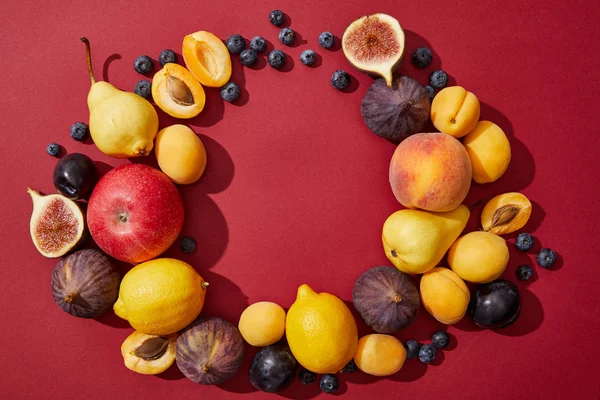 Vista superior de várias frutas frescas maduras e doces de verão no fundo vermelho — Fotografia de Stock