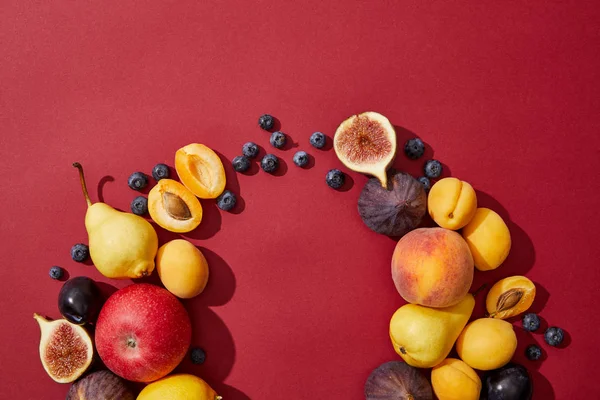 Vista superior de varias frutas dulces sabrosas frescas maduras sobre fondo rojo - foto de stock