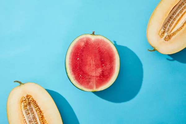 Vista superior de melón fresco maduro a la mitad dulce y sandía en azul - foto de stock