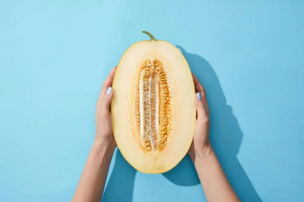 Abgeschnittene Aufnahme einer Person mit der Hälfte einer frischen reifen Melone auf blauem Grund — Stockfoto