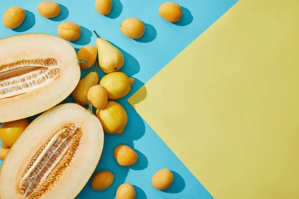 Sweet ripe melon, pears, lemons and apricots on yellow and blue background — Stock Photo