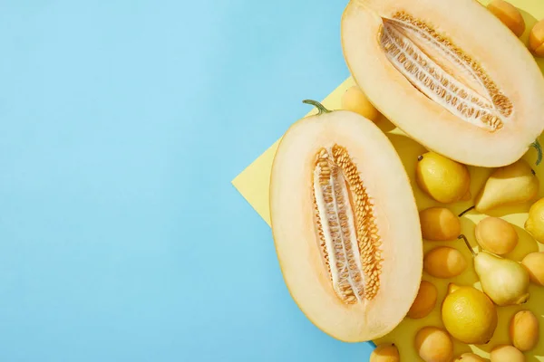 Draufsicht auf süße reife Melonen, Birnen, Zitronen und Aprikosen auf gelbem und blauem Hintergrund — Stockfoto