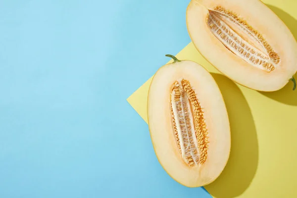 Top view of halved ripe melon on blue and yellow background — Stock Photo