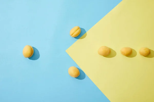 Vue de dessus des abricots frais mûrs sur fond bleu et jaune — Photo de stock