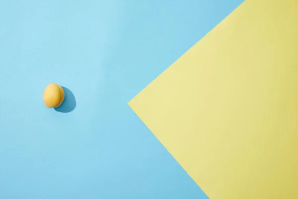 Вид сверху на один спелый абрикос на синем и желтом фоне — стоковое фото